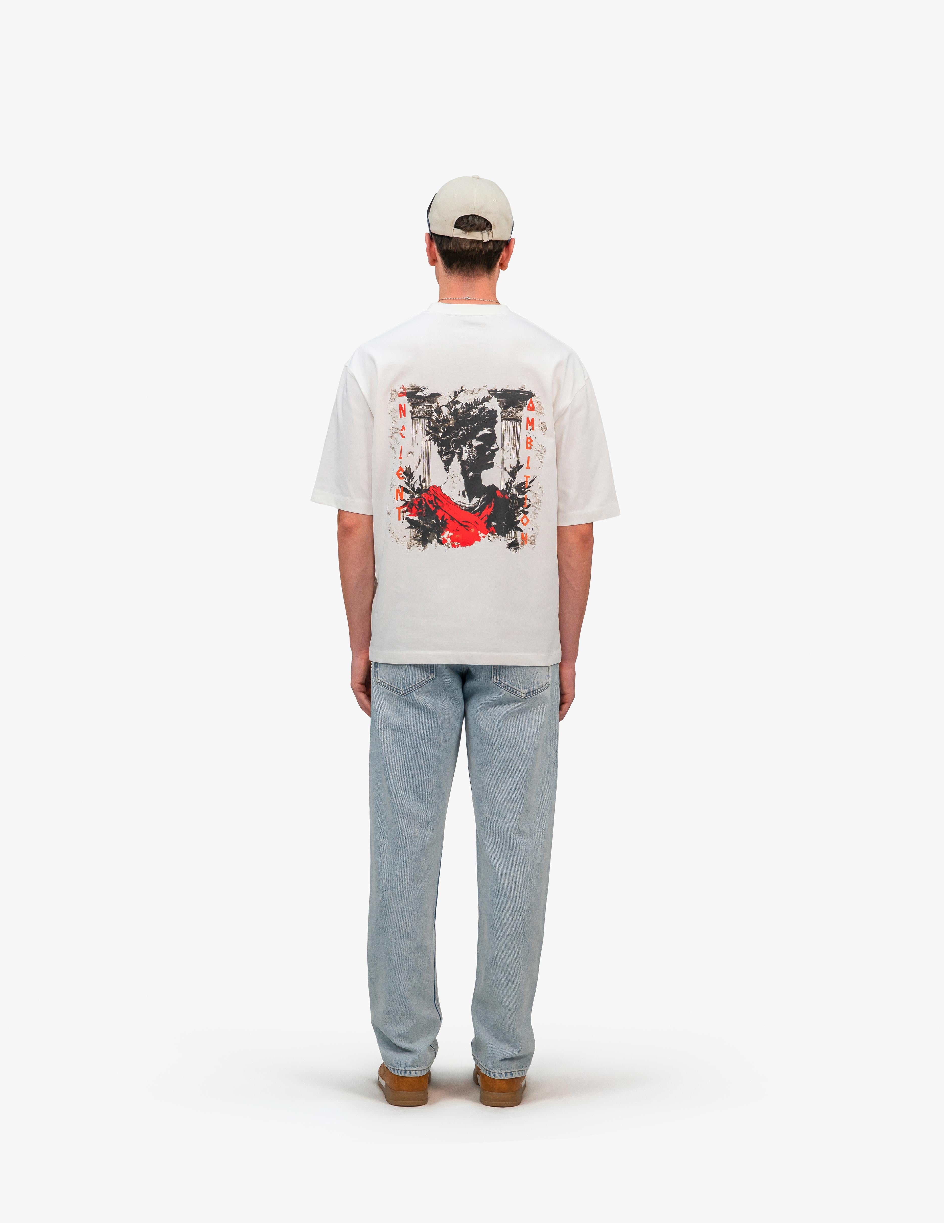 Ancient Ambition Vintage Off White Oversize Tişört, Beyaz bir stüdyo fonunun önünde, arkası dönük bir şekilde duran, kısa kahverengi saçlı ve bej renkli bir şapka takan bir erkek. Üzerinde sırtında siyah, beyaz ve kırmızı renklerde soyut bir grafik baskı bulunan beyaz, geniş kesim bir tişört ve açık mavi, bol kesim bir kot pantolon giyiyor. Ayaklarında kahverengi ayakkabılar bulunuyor. -  Faylit