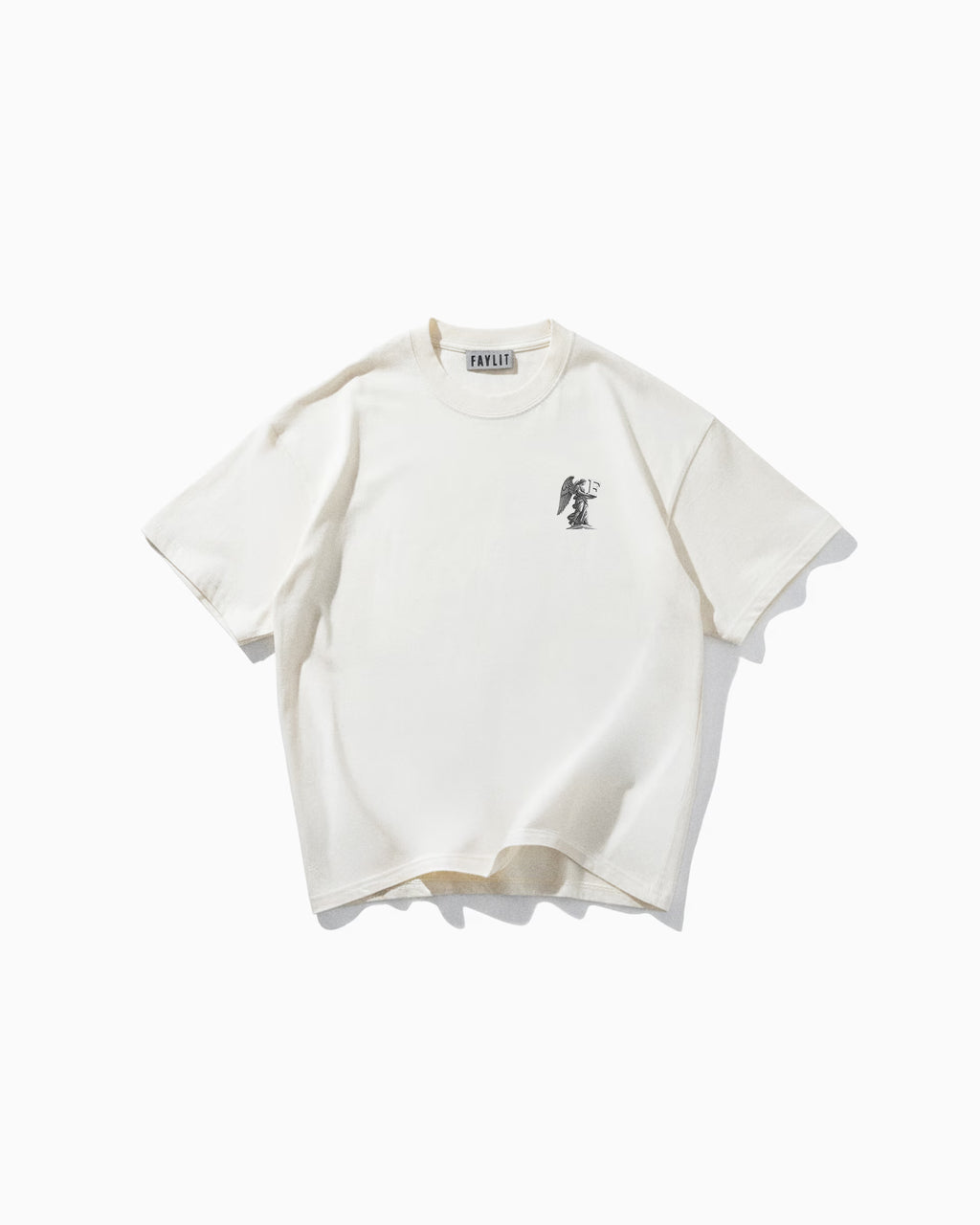 Angel Off White Oversize Tişört - Krem rengi (Off White) oversize tişörtün düz çekim ürün fotoğrafı. Tişörtün sol göğüs kısmında, siyah-beyaz detaylı bir baskı yer alıyor. Baskıda, elinde kılıç ve terazi tutan, zırhlı ve kanatlı bir melek (Başmelek Mikail) figürü resmedilmiş. Yaka içindeki "Faylit" marka etiketi görülebilmektedir.