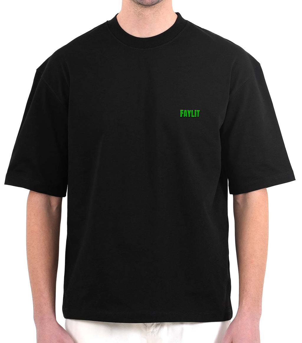 FDNA_01 Oversize Tişört - Siyah oversize tişört giyen erkek mankenin göğüs bölgesinin yakın çekimi. Tişörtün sol göğsünde, parlak neon yeşili renginde minimalist "FAYLIT" logosu bulunmaktadır. Tişörtün bol ve dökümlü kesimi modelin üzerinde görülmektedir. -  Faylit