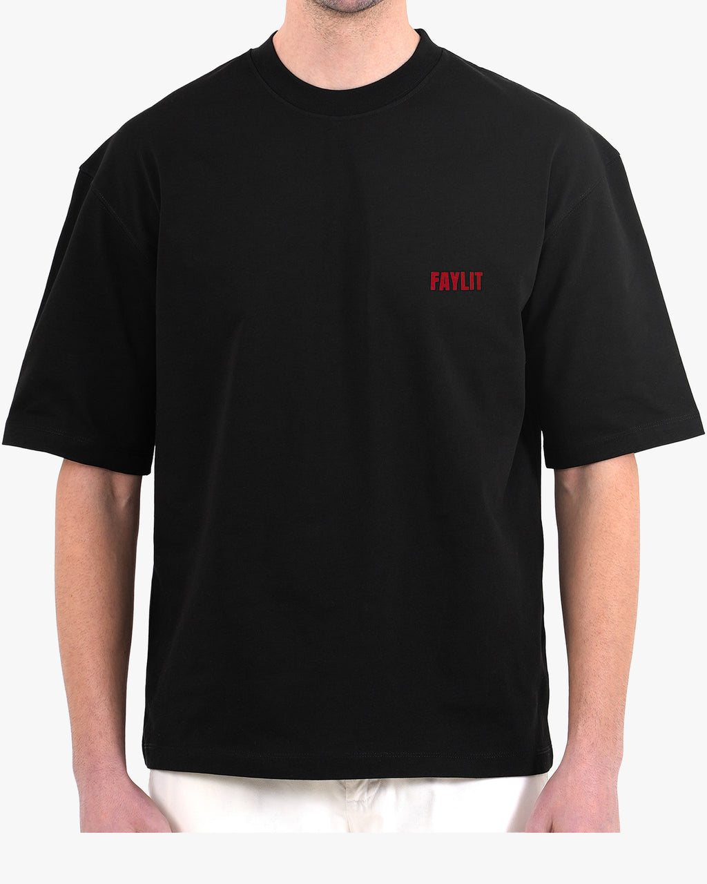 FDNA_02 Oversize Tişört - Siyah oversize tişört giyen erkek mankenin göğüs bölgesinin yakın çekimi. Tişörtün sol göğsünde, kırmızı renkte minimalist "FAYLIT" logosu bulunmaktadır. Tişörtün bol ve dökümlü kesimi modelin üzerinde görülmektedir. -  Faylit