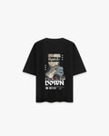 Upside Down Siyah Oversize Tişört - Siyah oversize tişörtün sırt yüzeyinin düz çekim ürün fotoğrafı. Tişörtün sırtında, kolaj tarzında tasarlanmış, büyük ve dikkat çekici bir baskı yer alıyor. Baskıda, ters çevrilmiş bir antik heykel parçası ve modern 3 boyutlu bir obje bulunuyor. Bu görselin üstünde "UPSIDE", altında ise gotik harflerle "DOWN" yazısı mevcut. Tasarım, barkod ve yıldız gibi küçük grafiklerle tamamlanmış. -  Faylit