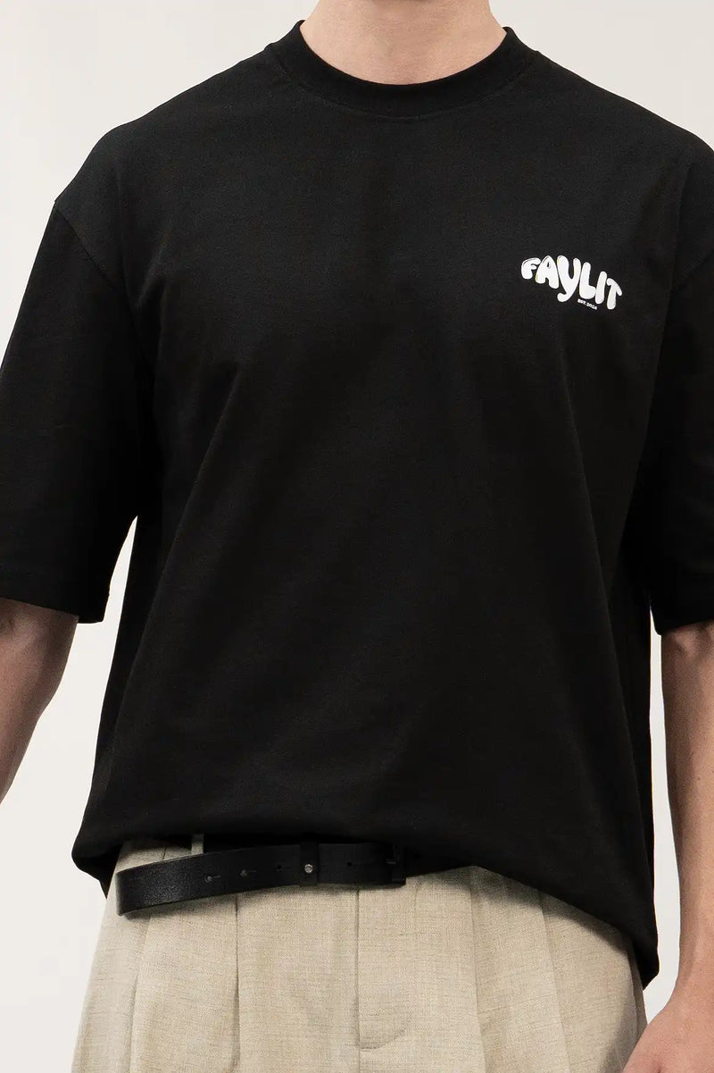 siyah oversize Faylit Marka giyen bir model. Siyah tişörtün önünde 'Faylit' motto yazısı dikkat çekiyor.