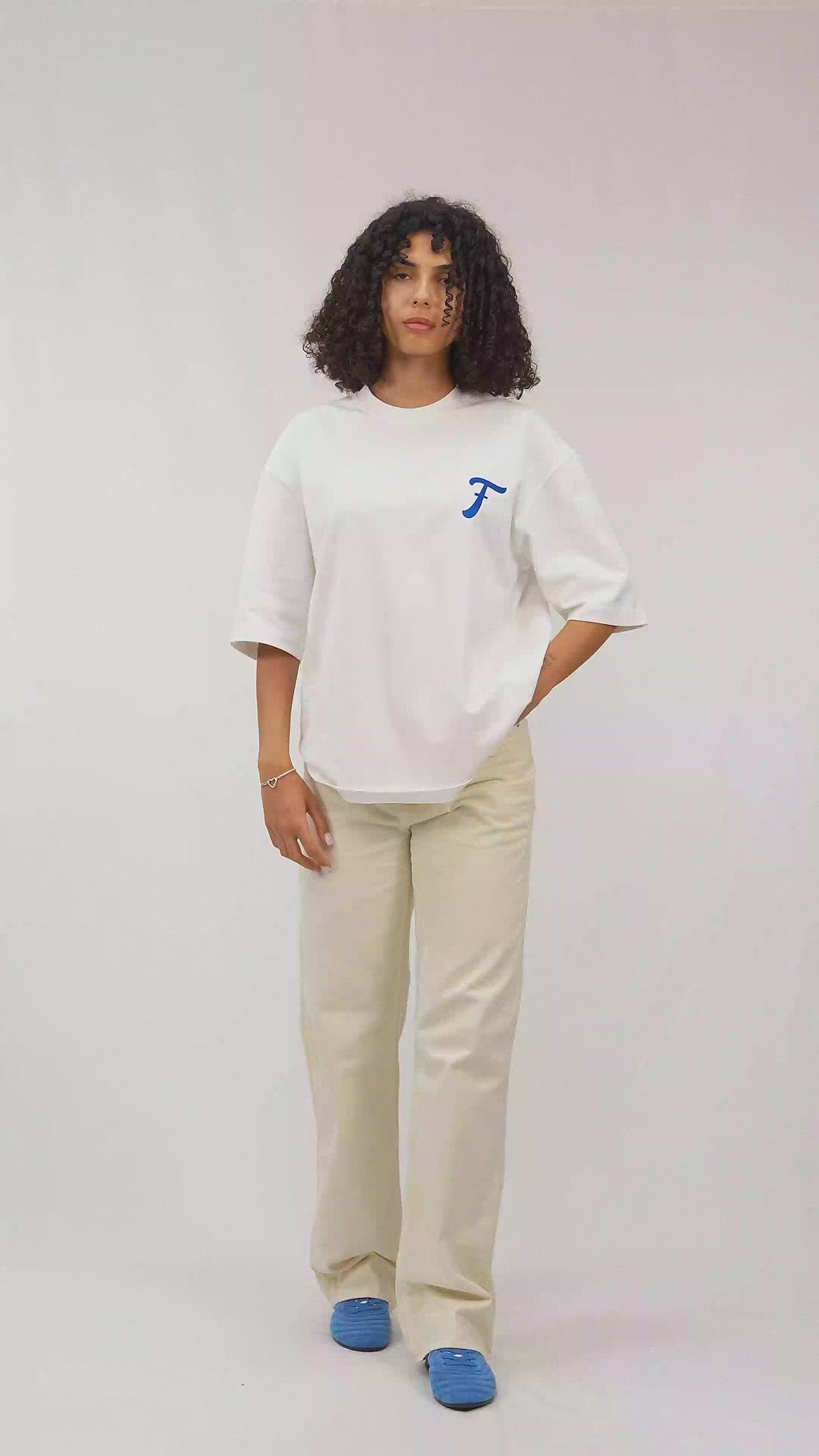 Akdeniz, Yunanistan esintilerini barındarn ekru tişört giymiş kıvırcık saçlı model Faylit Coast adlı tişörtü tanıtıyor. 